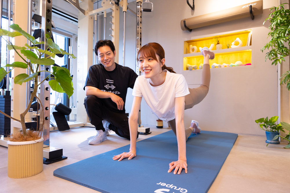 精神と時のジム二子玉川店でトレーナーのサポートを受けながら運動する様子